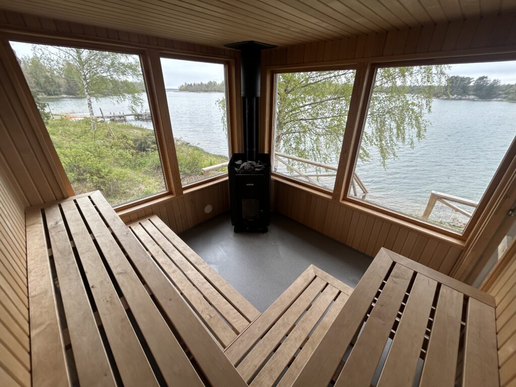 Fristående vedeldad bastu vid vattnet på Björkö med altan och stora fönster